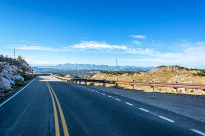 Road by mountain against blue sky