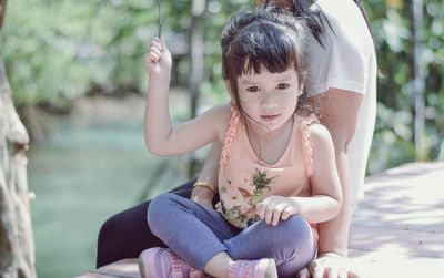 Happy girl sitting outdoors with mother