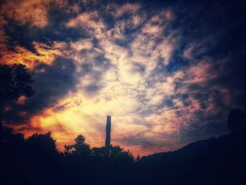 Low angle view of silhouette factory against sky during sunset