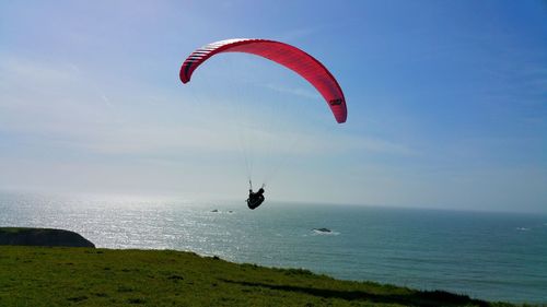 Man paragliding over sea against sky