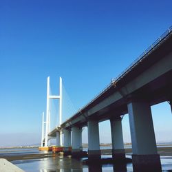 Low angle view of suspension bridge against blue sky