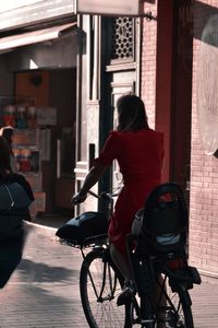 Rear view of woman with bicycle on street in city