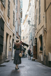 Rear view of people walking on street amidst buildings