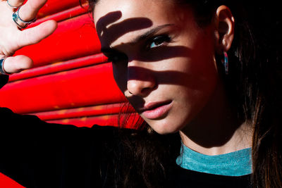 Close-up portrait of young woman shielding while standing outdoors during sunny day