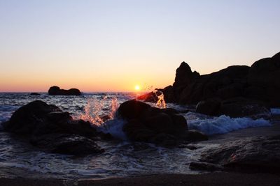 Scenic view of sea and rocks against clear sky