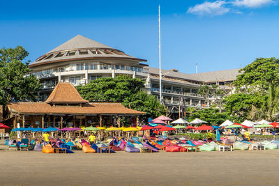 Multi colored umbrellas on beach by buildings against blue sky