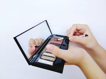 Midsection of person holding mobile phone against white background