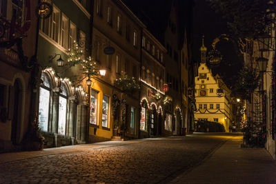 Illuminated alley amidst street in city at night