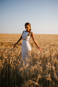 Bride standing amidst cereal plants on agricultural field