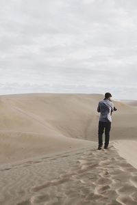 Rear view of man standing on sand dune at desert