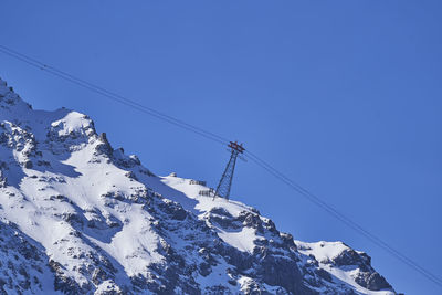 Low angle view of snowcapped mountain against blue sky