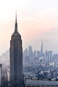 Modern buildings in city against sky during sunset