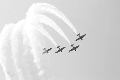 Low angle view of airshow against cloudy sky