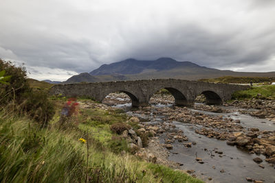 Arch bridge over mountains against sky