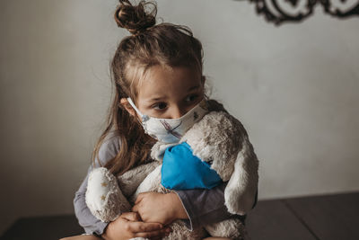 Portrait of cute girl sitting with toy at home