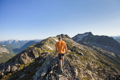 Rear view of man trail running on mountain ridge, b.c., canada.