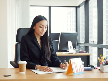 Mid adult woman using smart phone while sitting on table