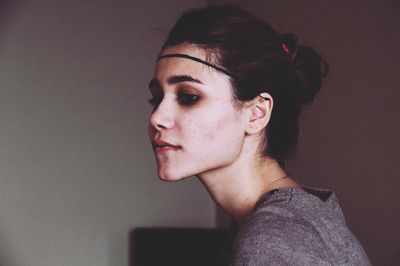 Portrait of young woman looking away against wall