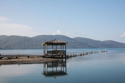 Built structure on pier at lake against sky