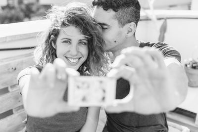 Couple in love holding an instant photo. horizontal view of young man kissing his girlfriend.