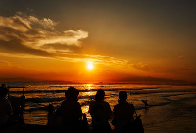 Silhouette people on beach against sky during sunset