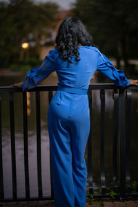 Rear view of woman standing against railing at park