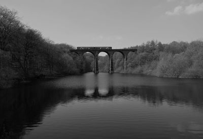 Arch bridge over river against sky