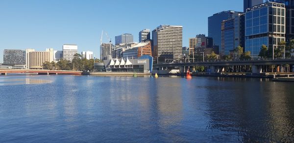 River by city buildings against clear sky