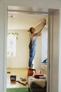 Woman sticking wallpaper on wall