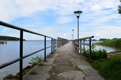 Walkway by sea against sky