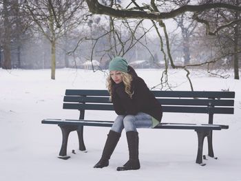 Woman sitting on bench during winter