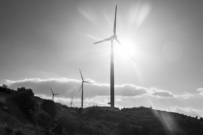 Low angle view of wind turbines on field against sky