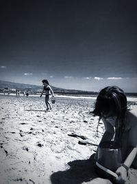 Siblings on beach against sky