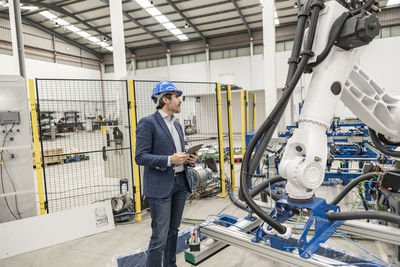 Engineer wearing hardhat standing with digital tablet pc in factory