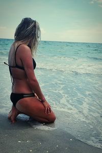 Young woman on beach against sky