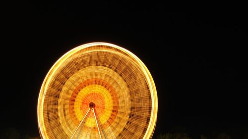 Illuminated ferris wheel against clear sky at night