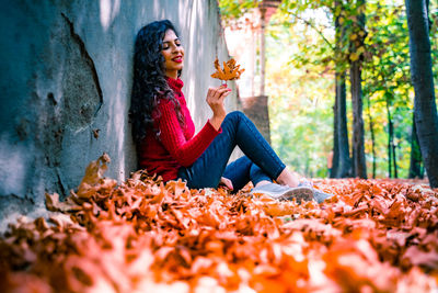 Woman sitting on leaves in park during autumn