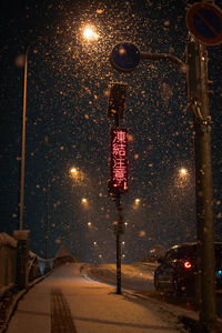 Illuminated street light on road in city at night