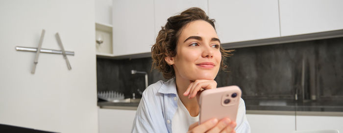 Portrait of young woman using mobile phone at home