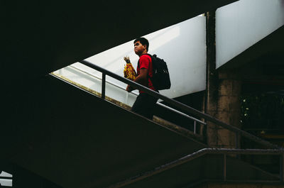 Young man standing on steps against sky