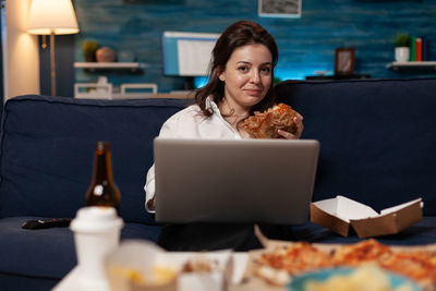 Young woman using laptop while sitting on table