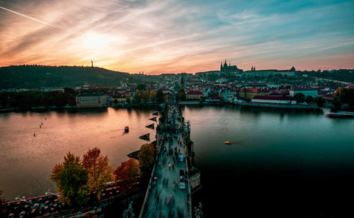 Bridge over river in city against sky during sunset