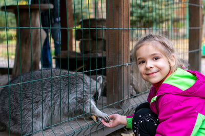 The girl feeds raccoons at the zoo. a child feeds a raccoon in a cage at the city zoo.  