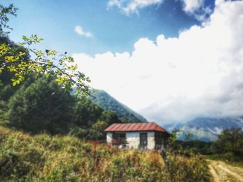 House on field by trees against sky