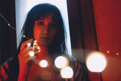 Portrait of woman holding illuminated lighting equipment