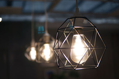 Close-up of illuminated light bulb hanging on ceiling