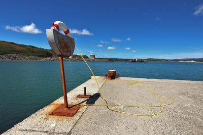 Deck chairs on shore against blue sky