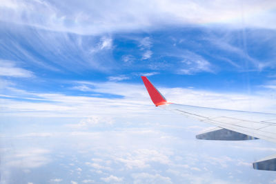 Airplane wing over clouds against sky