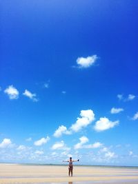 Mid distance of woman standing on sand against sea at beach