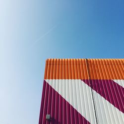 Low angle view of cargo container against clear blue sky